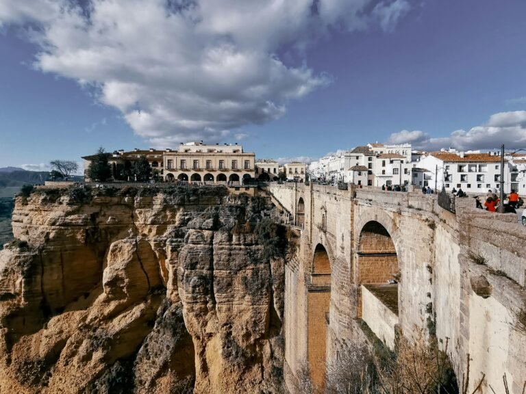 The iconic Puente Nuevo bridge spans the breathtaking gorge in Ronda, Spain, under a vibrant sky.