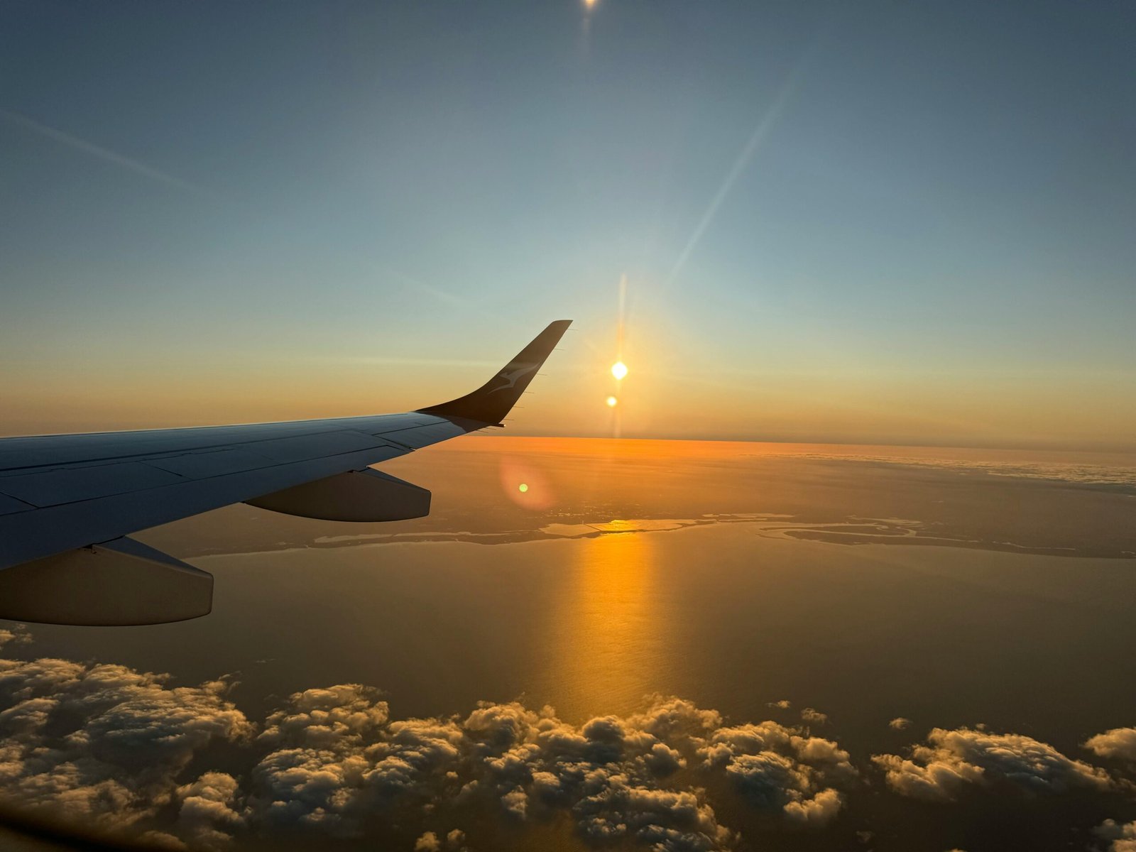 Capture of a mesmerizing ocean sunset viewed from an airplane window during flight.