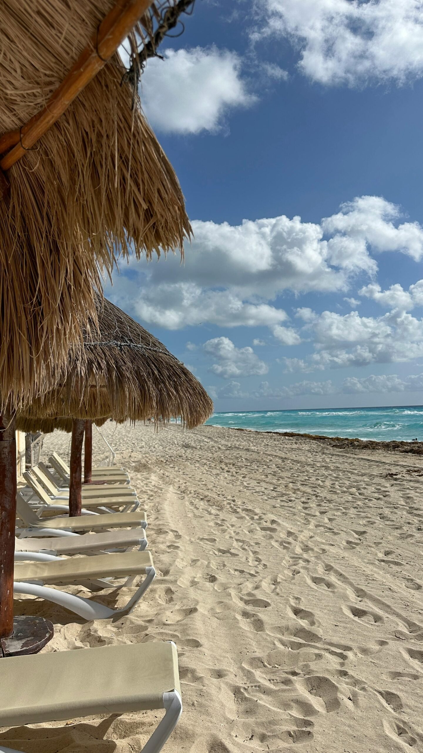 Scenic view of sandy beach with thatched umbrellas in Cancún, ideal for relaxation.